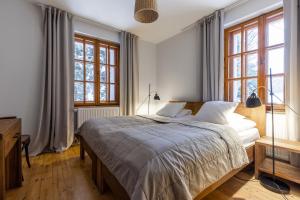 a bedroom with a large bed and windows at Biały Dom W ROPKI in Ropki
