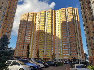 um grande edifício com carros estacionados num parque de estacionamento em Стильная и уютная квартира в новом доме на Оболони em Kiev