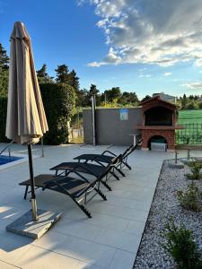 un gruppo di sedie e un ombrellone su un patio di Apartments Villa Ohana a Kaštela (Castelli)