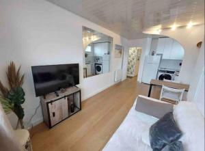 a living room with a white couch and a flat screen tv at Vue MER/Tout à pied/Calme/Plage/ Parc Mauresque in Arcachon