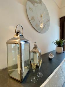 eine Uhr und zwei Gläser Wein auf der Theke in der Unterkunft White Pearl - Luxury in Giardini-Naxos