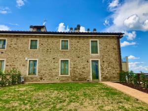 a large brick building with a grass yard in front of it at Sangi Chianti Vacations in Poggibonsi