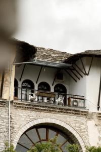 a building with a balcony with tables and chairs on it at Emblematic House Apartment 1 in Gjirokastër