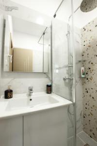 a white bathroom with a sink and a shower at Emblematic House Apartment 1 in Gjirokastër