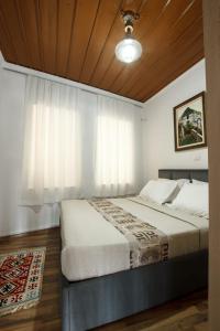 a bedroom with a large bed with white curtains at Emblematic House Apartment 1 in Gjirokastër