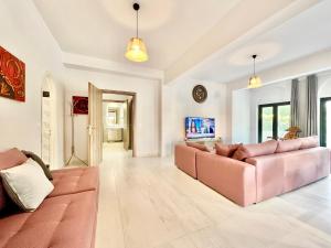 a living room with a pink couch and a tv at Villa Trousas Kassiopi with private pool in Kassiopi