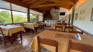 un restaurante con mesas, sillas y ventanas en La Casa de Pipa, en Mina Clavero