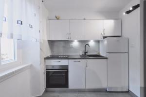 een witte keuken met een wastafel en een koelkast bij Apartment Z in Zlarin