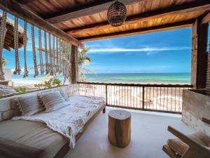 a porch with a bed and a view of the beach at Amansala Resort in Tulum