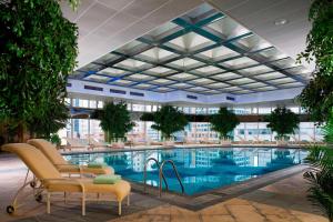 - une grande piscine dans un bâtiment avec des chaises et des arbres dans l'établissement The Hongta Hotel, A Luxury Collection Hotel, Shanghai, à Shanghai