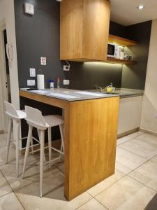 a kitchen with a counter and a sink and chairs at Apart Rivadavia340 in Neuquén