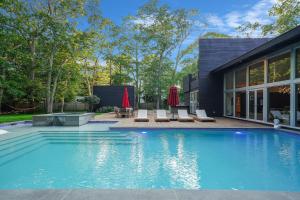 a swimming pool with chairs and a house at Enjoy the Spa all year round in this EHV Estate in East Hampton