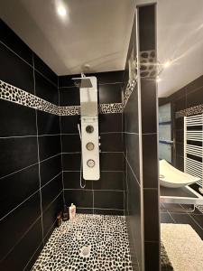 uma casa de banho com um chuveiro e uma parede de azulejos pretos em Appart en duplex climatisé cœur de ville em Périgueux