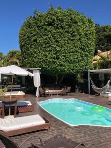 a swimming pool with chairs chairs and an umbrella at Pousada Aloha Beach House in Praia do Rosa