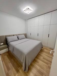 Center of Tirana - Apartment في تيرانا: غرفة نوم بسرير كبير ودواليب بيضاء