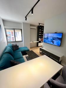 Center of Tirana - Apartment في تيرانا: غرفة معيشة مع أريكة زرقاء وتلفزيون بشاشة مسطحة