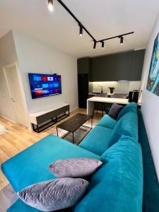 Center of Tirana - Apartment في تيرانا: غرفة معيشة مع أريكة زرقاء وتلفزيون