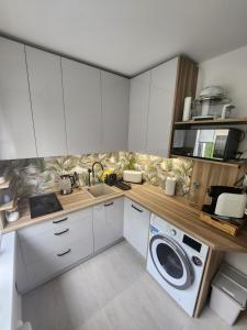 eine Küche mit weißen Schränken und einer Waschmaschine in der Unterkunft Moon Apartment in Breslau