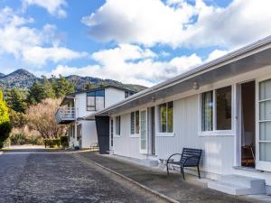 a bench sits outside of a building with mountains in the background at Rainbow Motel & Hot Pools in Turangi