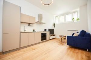 a living room with a blue couch and a kitchen at MILANO URBAN FLATS Modern apartments few minuts from Duomo in Milan