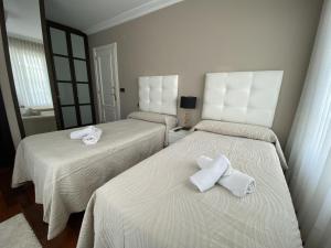 two beds with white towels on them in a room at Villa OLYMPIA in Castro-Urdiales