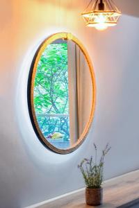 a round mirror on a wall with a window at NikoleTakis Apartments in Paralia Panteleimonos