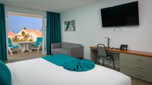 ein Hotelzimmer mit einem Bett und einem Schreibtisch mit einem TV in der Unterkunft Captain Don's Habitat in Kralendijk