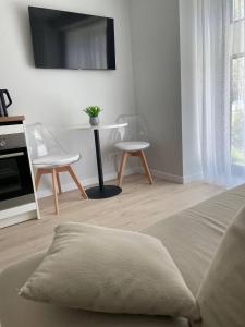 a bedroom with a bed and two chairs and a tv at Three By The Sea apartments at Albatross Home in Ķesterciems
