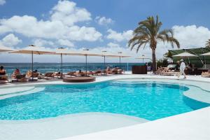 a swimming pool at a resort with people sitting at AMA Ibiza in Playa d'en Bossa