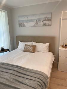 a bedroom with a white bed with a picture on the wall at Three By The Sea apartments at Albatross Home in Ķesterciems