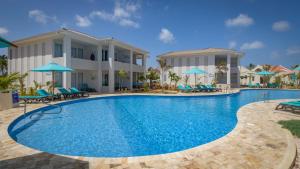 a pool at a resort with chairs and umbrellas at Captain Don's Habitat in Kralendijk