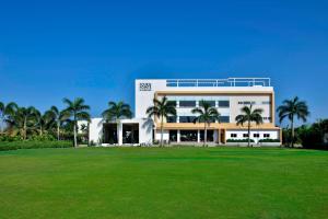 a large building with palm trees in front of a field at Four Points by Sheraton Mahabalipuram Resort & Convention Center in Mahabalipuram