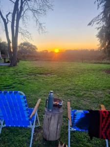 2 Stühle und ein Tisch auf einem Feld mit Sonnenuntergang in der Unterkunft La Monedita in Torres