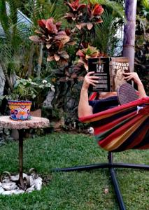 a person sitting in a chair reading a book at SOL Y SALSA bnb in Cuernavaca