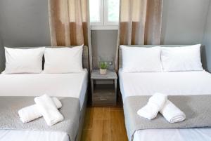 Duas camas num quarto com lençóis e almofadas brancos em NikoleTakis Apartments em Paralia Panteleimonos