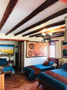 a bedroom with two beds and a painting on the wall at Hotel Villa Cristina in Villa de Leyva