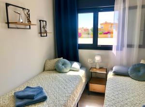 1 dormitorio con 2 camas con almohadas azules y ventana en Villa Salamander en El Verger