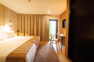 アルママールにあるHotel Folgosa Douroのベッドとデスクが備わるホテルルームです。