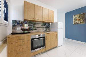 a kitchen with wooden cabinets and a stove top oven at Villa Rosmarin - family friendly, beachfront in Pašman
