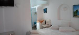 Habitación blanca con cama y silla en Dimitris Studios, en Perissa