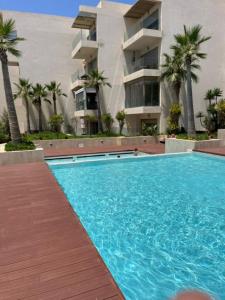 einem Pool vor einem Gebäude mit Palmen in der Unterkunft Appartement de haut standing. in Mohammedia