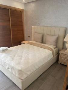 ein Schlafzimmer mit einem großen weißen Bett in einem Zimmer in der Unterkunft Appartement de haut standing. in Mohammedia