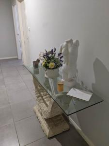 une table en verre avec une statue et des fleurs. dans l'établissement Country Lane, à Horningsea Park