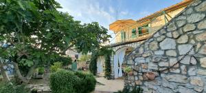 a stone building with a balcony and a stone wall at Stone House with garden Laganini in Zlarin