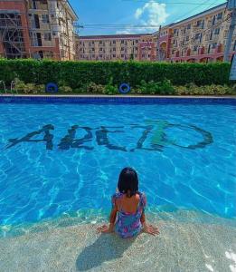 a little girl sitting in front of a swimming pool at Italian Inspired Condo in Davao by AAG in Davao City