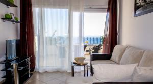a living room with a couch and a large window at Apartments Maris in Baška Voda