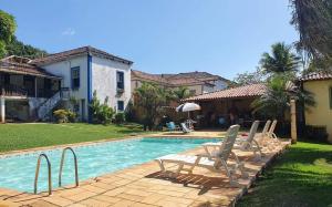 einen Pool mit zwei Stühlen und ein Haus in der Unterkunft Casa do Barão, São José das Três Ilhas in Belmiro Braga