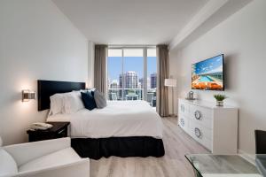 a white bedroom with a large bed and a couch at City View Balcony steps from Restaurants, Peacock Park & Marina in Miami