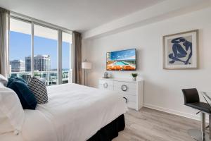 a white bedroom with a large bed and a window at City View Balcony steps from Restaurants, Peacock Park & Marina in Miami