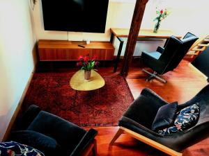 a living room with chairs and a table and a television at Loft de la raquette in Mons